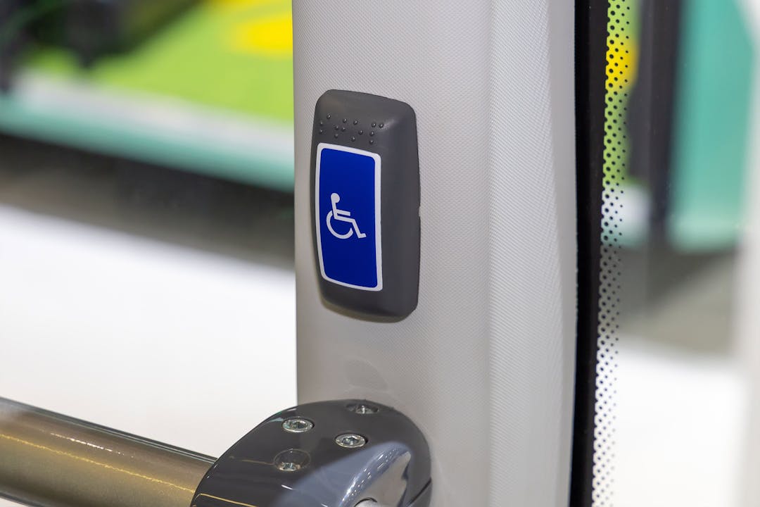 På innsiden av en buss hvor en blå knapp med rullestolsymbol er avbildet.